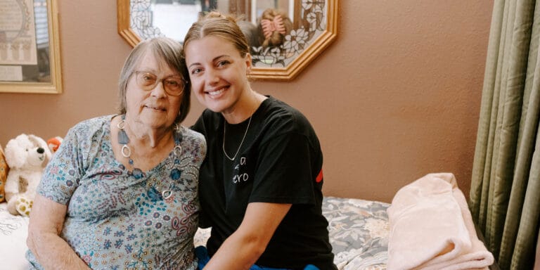 Senior resident and staff member smiling together in a cozy room