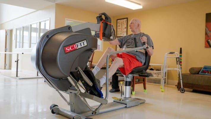 Senior using a leg exercise machine in a fitness area