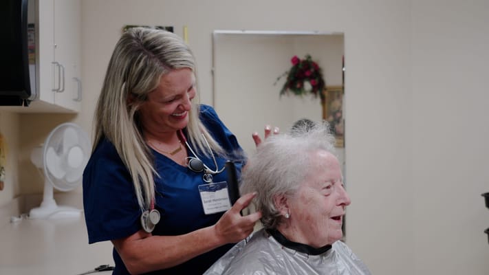 Staff member doing hair for a resident in a salon