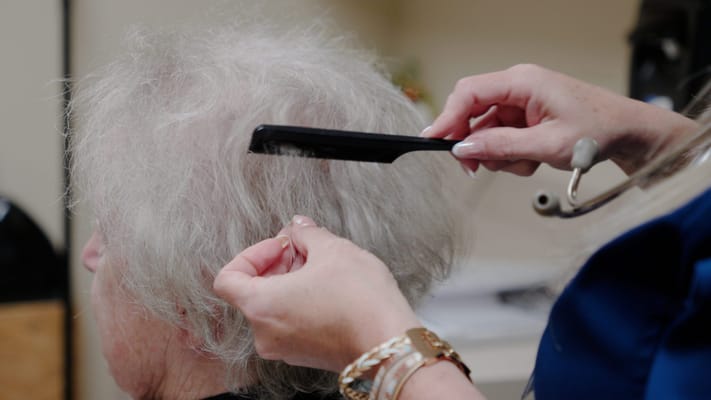 Caregiver styling a resident's hair in a facility