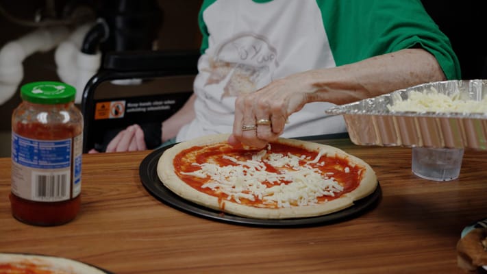 Resident preparing a pizza during a cooking activity