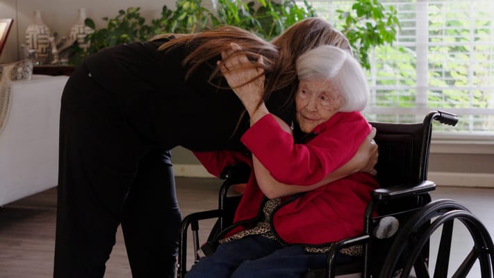 A caregiver and a resident sharing a warm hug