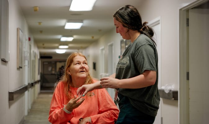 A caregiver assisting a resident in a hallway