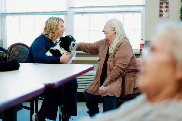 Residents interacting with a staff member and a dog