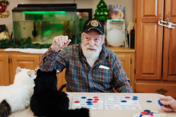 Resident playing bingo with cats beside him