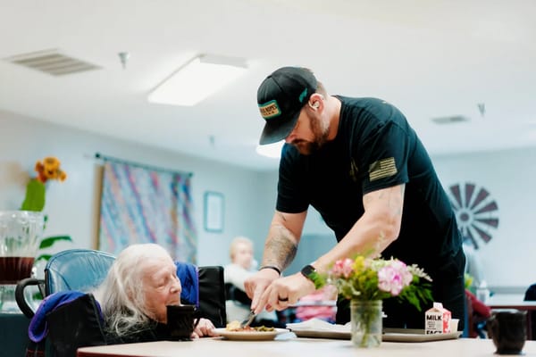 Caregiver serving food to a resident in a common area