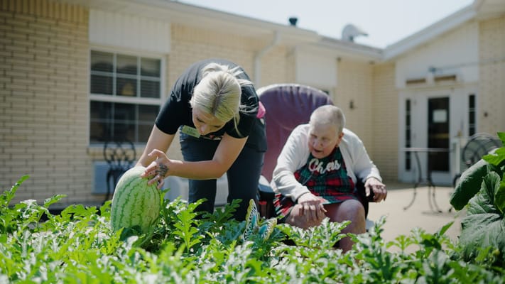 Resident and staff gardening in a community space