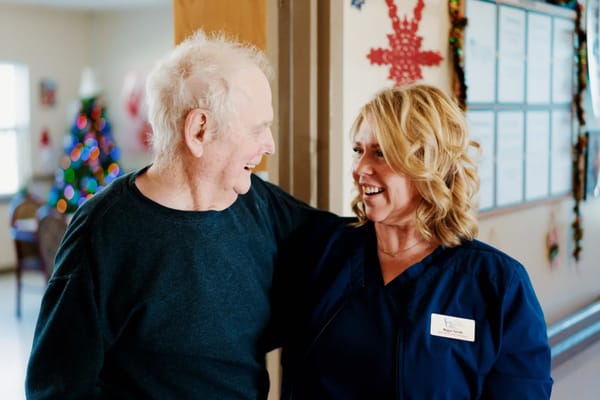 Resident and staff member smiling together in a hallway