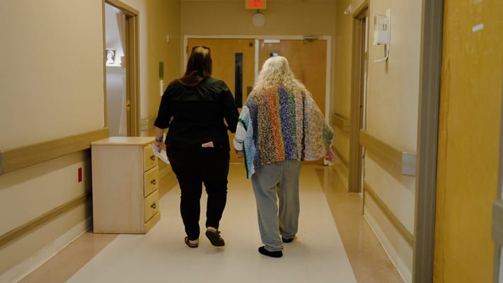 Two women walking down a hallway in a care facility