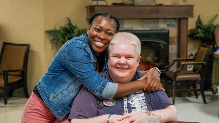 A caregiver and resident smiling together in a common area