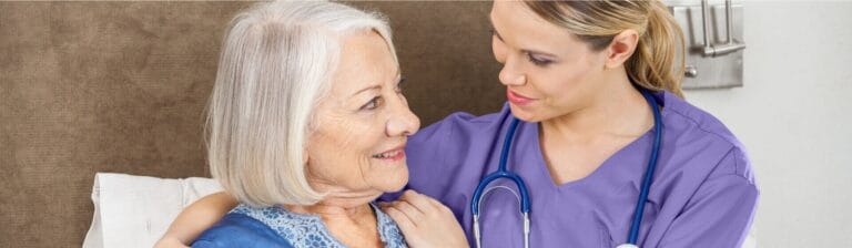 A caregiver smiling with a senior resident in a room