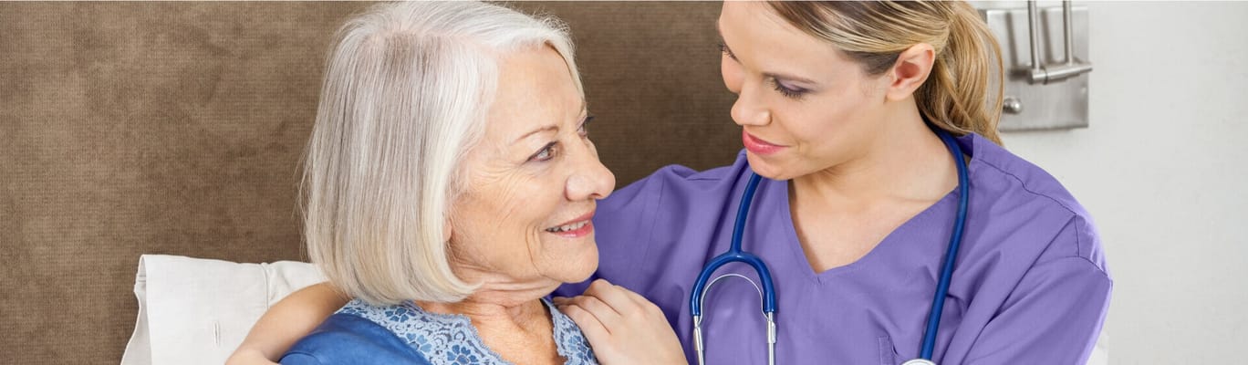 A caregiver smiling with a senior resident in a room