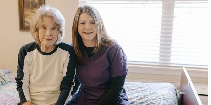 A caregiver and resident smiling in a personal room
