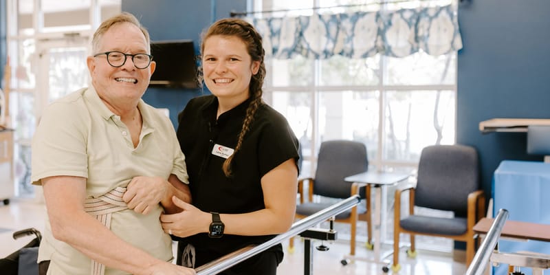 A resident and staff member smiling together in a therapy area