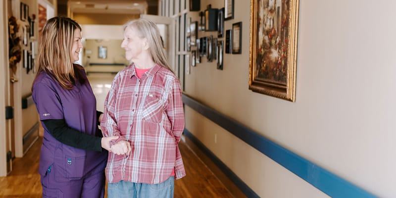 Staff member assisting a resident in a hallway