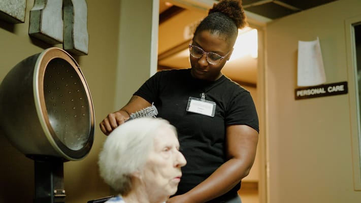 A staff member giving a resident a hairstyle