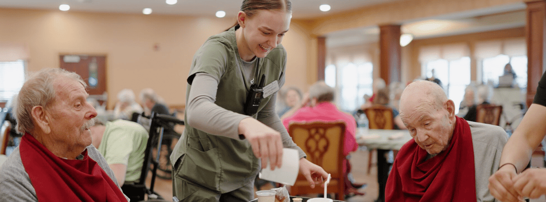 Staff serving food to residents in a dining room