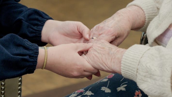 A caregiver holding hands with a senior resident