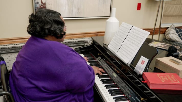 Resident playing piano in a vibrant common area