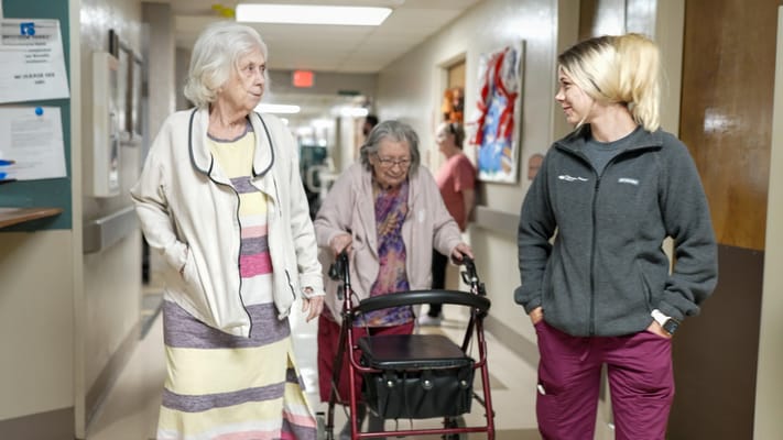 Residents walking with staff in a facility hallway