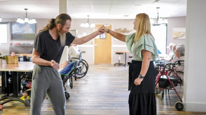 Residents dancing with a staff member in a common area