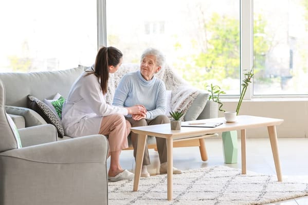 Senior resident talking with a caregiver in a cozy living room