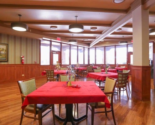 Dining area with red tablecloths and large windows