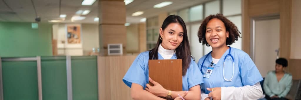 Two staff members smiling in a facility hallway