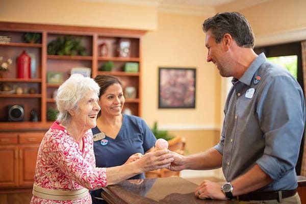 Resident receiving an ice cream from staff in a warm setting