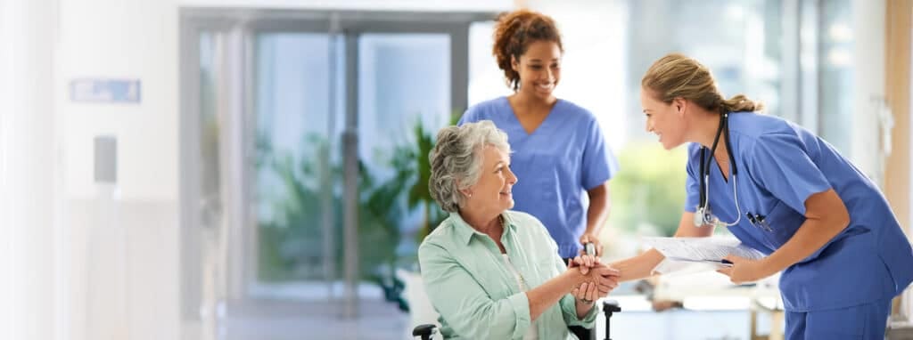 Healthcare staff interacting with a resident in a hallway