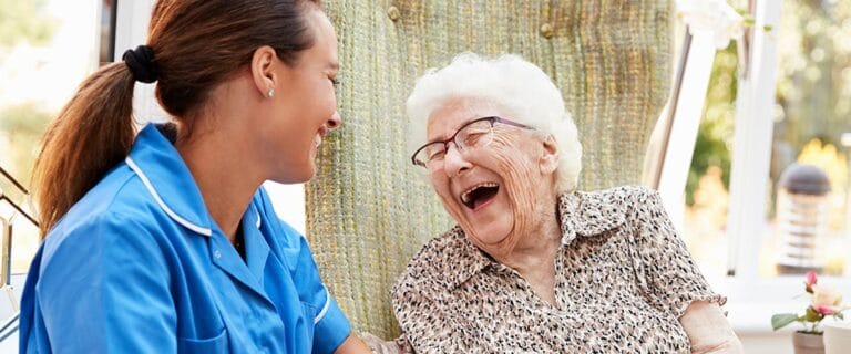 Caregiver laughing with a resident outdoors