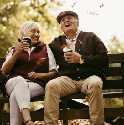Seniors enjoying coffee together on a park bench