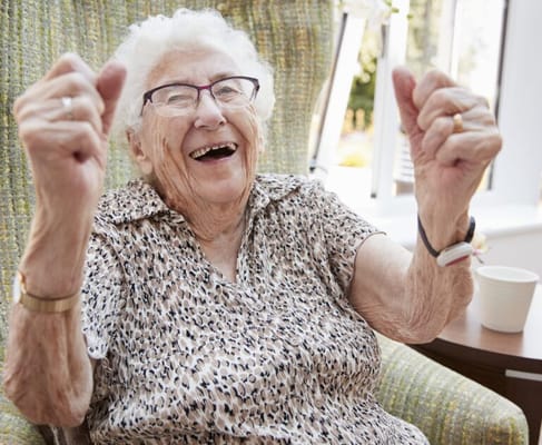Elderly woman joyfully celebrating in her chair