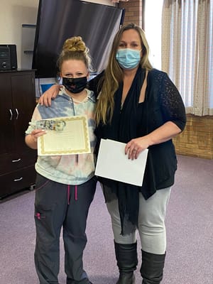Two staff members posing with an award certificate