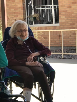 A smiling resident in a wheelchair outdoors