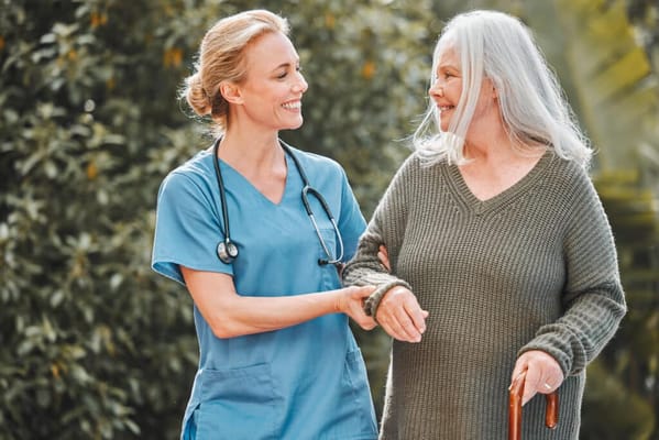A caregiver assisting a senior woman in a garden