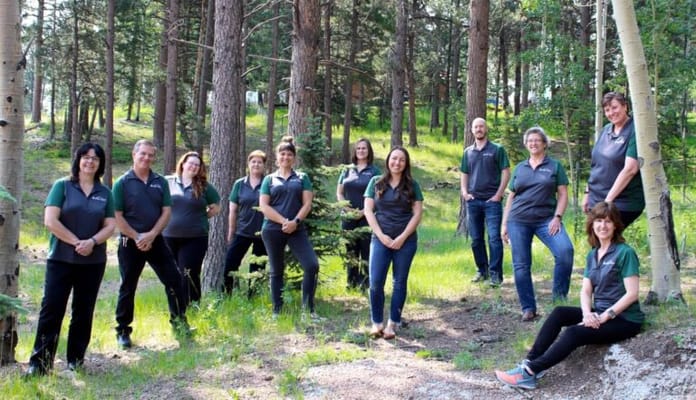 Staff posing together in a forested outdoor area