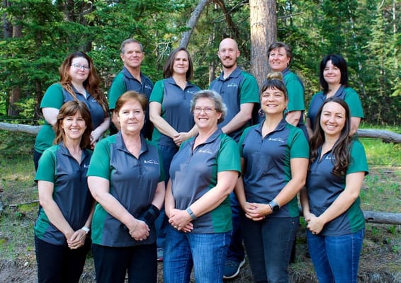 Staff members posing in a forested outdoor area