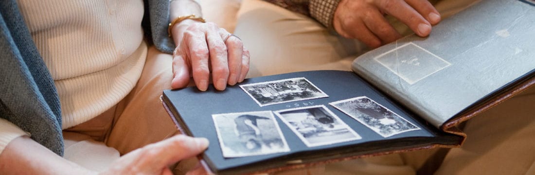 Close-up of elderly individuals looking at a photo album