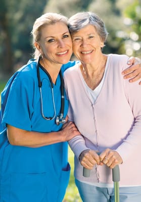 A caregiver and a resident smiling together outdoors