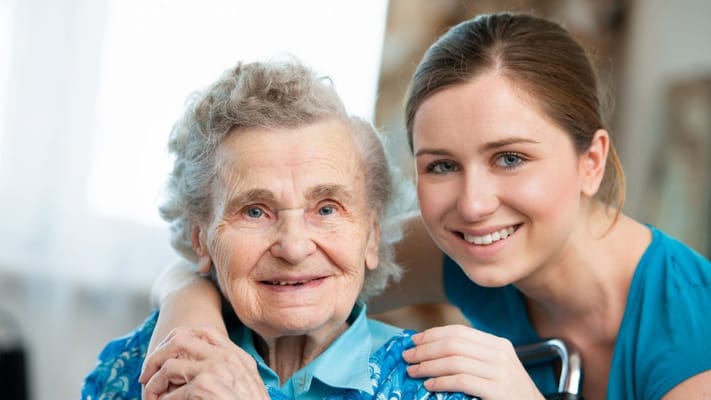 A caregiver with an elderly resident smiling together