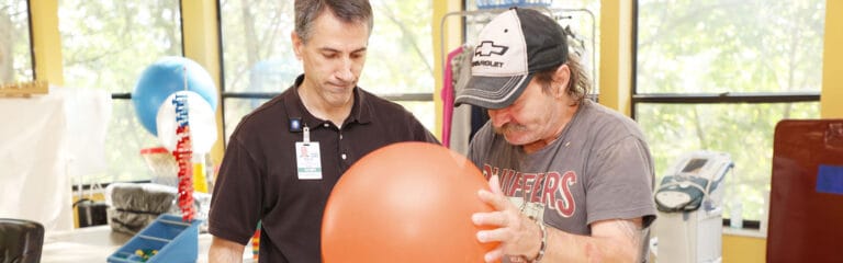 Therapist assisting resident with an exercise ball