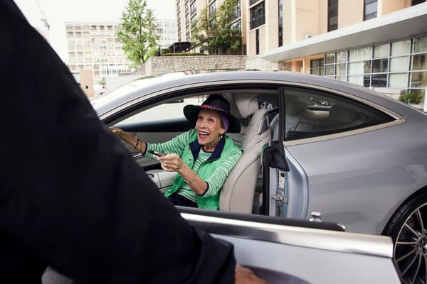 Elderly woman happily interacting with a caregiver in a car