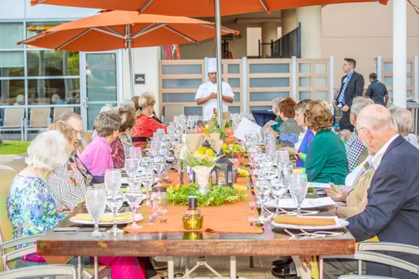 Residents enjoying a meal outdoors with a chef present