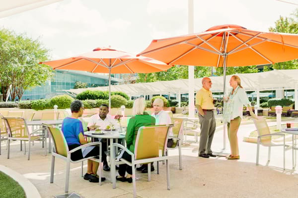 Residents enjoying lunch outdoors under orange umbrellas