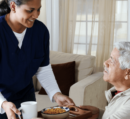 Caregiver serving food to a senior resident