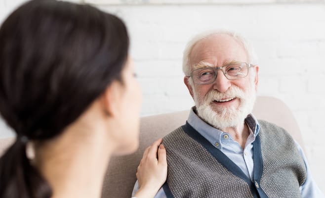 Smiling elderly man in conversation with a caregiver