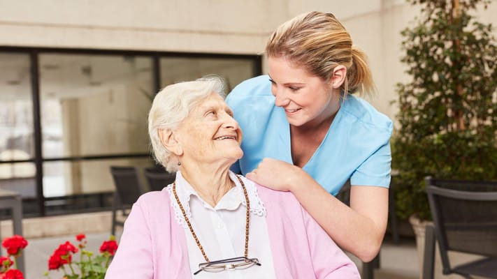 A caregiver interacting with a senior resident outdoors