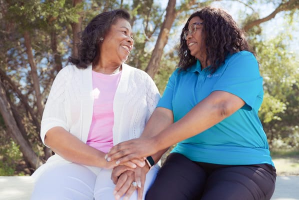 Two women smiling and chatting in a garden