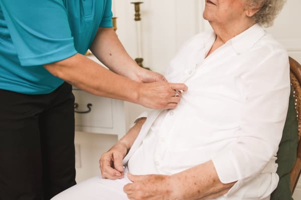 Staff assisting a senior resident in a warm setting